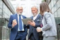 Small mixed group of businessmen and businesswoman meeting in front of a glass facade office building during coffee break