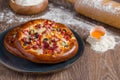 Small mixed pizza with pepperoni, sausage and cheese on wooden table Royalty Free Stock Photo