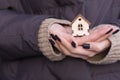 A small model of a wooden house stands on a hand. Concept image of my house