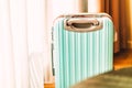 Small modern luggage with two-tone color, front view, stand on the wooden floor in a hotel room, background of white curtain,