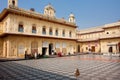 Small monkey and indian people sit in the white and black tiled courtyard