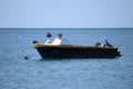 Small motorboat with dropped anchor on the sea, occupied by birds