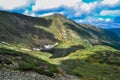 small mountain lake in the form of a heart among snowy glaciers, green mountain ranges overgrown with trees, Chersky peak Royalty Free Stock Photo