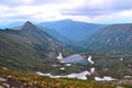 small mountain lake in form of a heart among snowy glaciers, green mountain ranges overgrown with trees, Chersky peak Royalty Free Stock Photo