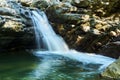 Small mountain waterfall among the rocks, the water is blurred in motion Royalty Free Stock Photo