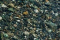 Small multicolored stones on the bank of a mountain stream with crystal clear glacial water. Top view. Royalty Free Stock Photo