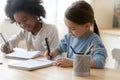 Small multiracial children enjoying preparing homework indoors.