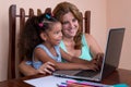 Small multiracial girl and her mother working on a laptop comput