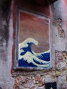 Small mural of Hokusai`s The Wave in a window of an abandoned brick house