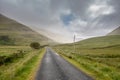 Small narrow asphalt road into mountains, Connemara, Ireland. Low cloudy sky. Nature background. Nobody. Rural area Royalty Free Stock Photo