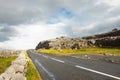 Small narrow asphalt road between traditional stone fence and rock . Burren area, West coast of Ireland. Warm sunny day. Cloudy Royalty Free Stock Photo