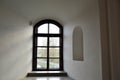 A small narrow black window with a frame on an old ancient stone white thick concrete wall in an old castle. The background Royalty Free Stock Photo