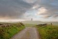 Small narrow country road to Moher Tower at Hag`s Head, county Clare, Ireland. Selective focus. Beautiful cloudy sky. Background Royalty Free Stock Photo