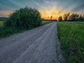 Small narrow road in a country side without asphalt at sunset, stunning colorful sky. Nobody. Nature scenery. Latvia rural area Royalty Free Stock Photo