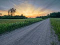 Small narrow road in a country side without asphalt at sunset, stunning colorful sky. Nobody. Nature scenery. Latvia rural area Royalty Free Stock Photo