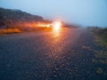 Small narrow road surface and illuminated car parked off the road. High quality asphalt surface wet after rain. Dangerous driving Royalty Free Stock Photo