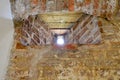 A small narrow window on an old, ancient, cracked stone shabby brick wall of red brick in the basement. The background Royalty Free Stock Photo