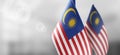 Small national flags of the Malaysia on a light blurry background