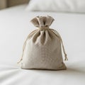 A small, neutral-toned drawstring pouch sits on a white surface. The pouch is made of Royalty Free Stock Photo