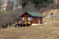 Small newly built wooden mountain cabin with front porch supported with wooden poles and new roof on side of hill Royalty Free Stock Photo