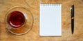Small notebook with a Cup of tea, stick on a rustic wood background. Royalty Free Stock Photo