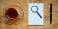 Small notebook with a Cup of tea, stick on a rustic wood background. Royalty Free Stock Photo