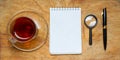 Small notebook with a Cup of tea, stick on a rustic wood background. Royalty Free Stock Photo