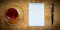 Small notebook with a Cup of tea, stick on a rustic wood background. Royalty Free Stock Photo