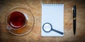 Small notebook with a Cup of tea, stick on a rustic wood background. Royalty Free Stock Photo