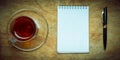 Small notebook with a Cup of tea, stick on a rustic wood background. Royalty Free Stock Photo