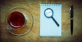 Small notebook with a Cup of tea, stick on a rustic wood background. Royalty Free Stock Photo