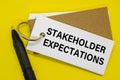 Small notebook labeled STAKEHOLDER EXPECTATIONS with clip on white background Royalty Free Stock Photo