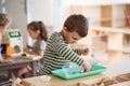 Small nursery school boy playing indoors in classroom, montessori learning.