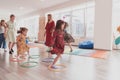 Small nursery school children with female teacher on floor indoors in classroom, doing exercise. Jumping over hula hoop Royalty Free Stock Photo