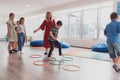 Small nursery school children with female teacher on floor indoors in classroom, doing exercise. Jumping over hula hoop Royalty Free Stock Photo