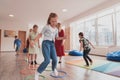 Small nursery school children with female teacher on floor indoors in classroom, doing exercise. Jumping over hula hoop Royalty Free Stock Photo