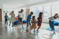 Small nursery school children with female teacher on floor indoors in classroom, doing exercise. Jumping over hula hoop Royalty Free Stock Photo