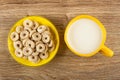 Oat rings in yellow saucer, cup with milk on table Royalty Free Stock Photo