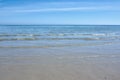 Small ocean waves on the shore against a clear blue sky with copy space. Landscape of the wide open sea or beach with Royalty Free Stock Photo