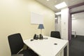 Small office cubicle with white desk and two twin black chairs, s