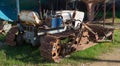 A small old abandoned bulldozer is rusting in a yacht yard