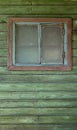 A small old closed window in green rustic wooden wall of an old house Royalty Free Stock Photo