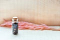 Small old vintage glass bottle with cork with floral tea and blue and pink petals on wooden background with spikelets . Organic