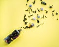 Small old vintage glass bottle with defocused floral tea and blue and pink petals inside and scattered tea petals and flowers on Royalty Free Stock Photo