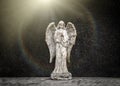 Small old weathered stone weeping angel with wings ornament standing in sorrow on black granite grave headstone in peaceful church Royalty Free Stock Photo