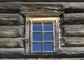 Small Old window with glass with a blue sky on the background of the wooden wall of the countryside log house