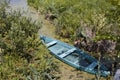 Small old wooden fishing punt boat in water at the bank of a lake, bright sunny summer day Royalty Free Stock Photo