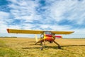 Small old yellow and red plane standing in summer field front view