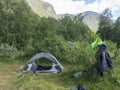 Small open tent with backpack and hiking gear in Swedish Lapland Landscape with green hills, mountain and birch forest