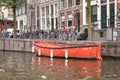 Small orange boat moored at the side of an urban canal quayside